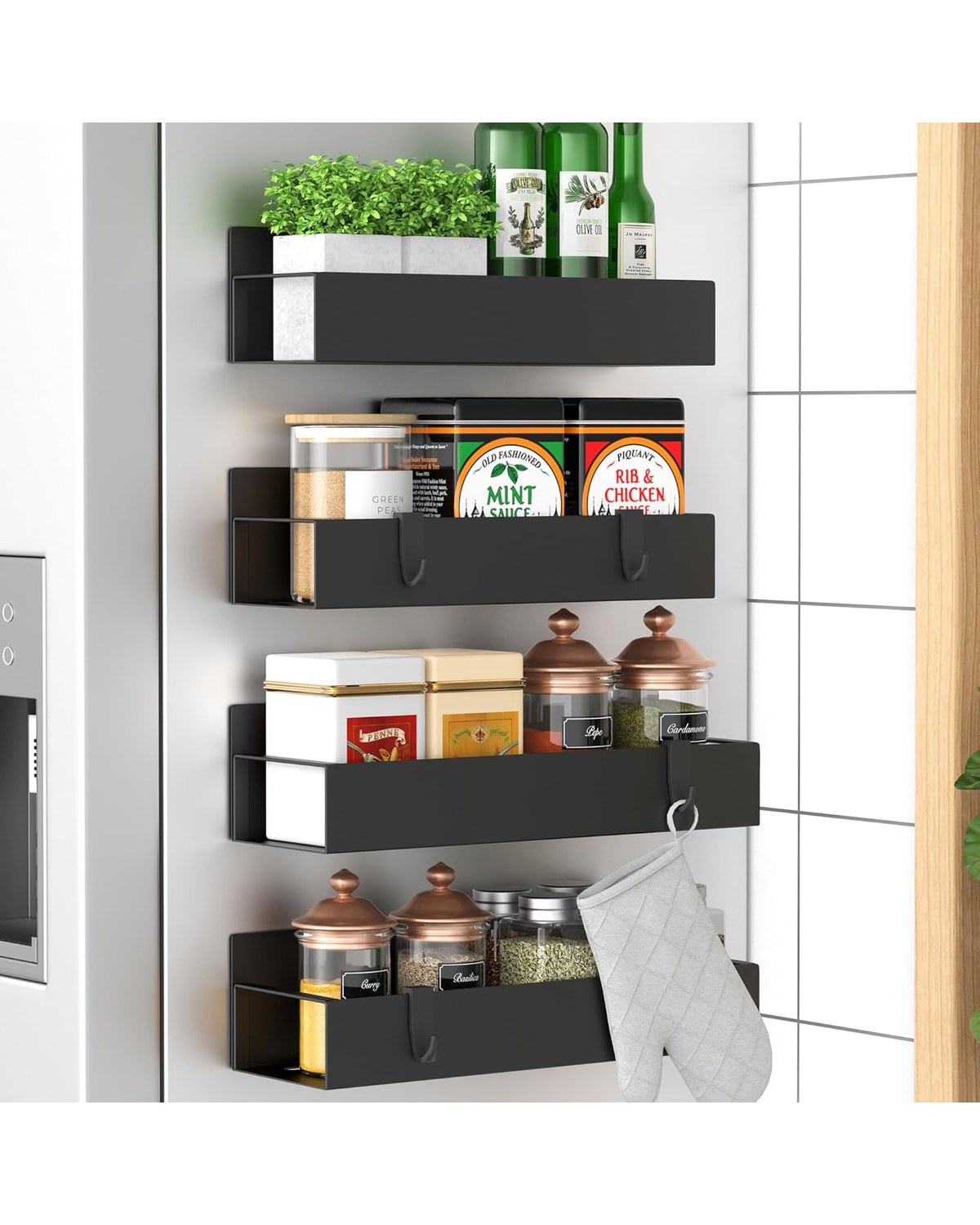 Four round stainless-steel magnetic spice tins mounted in a neat row on a brushed stainless refrigerator door, each with a hand-labeled lid visible from above.