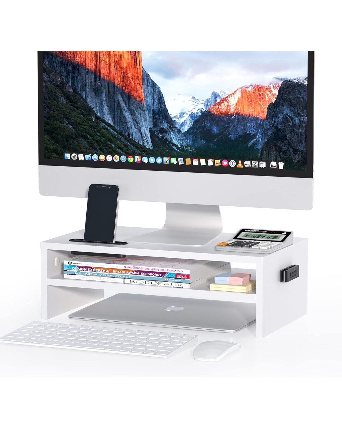 A clean white wood monitor stand on a minimalist desk with a MacBook laptop elevated above a wireless keyboard, small desk plant visible underneath.