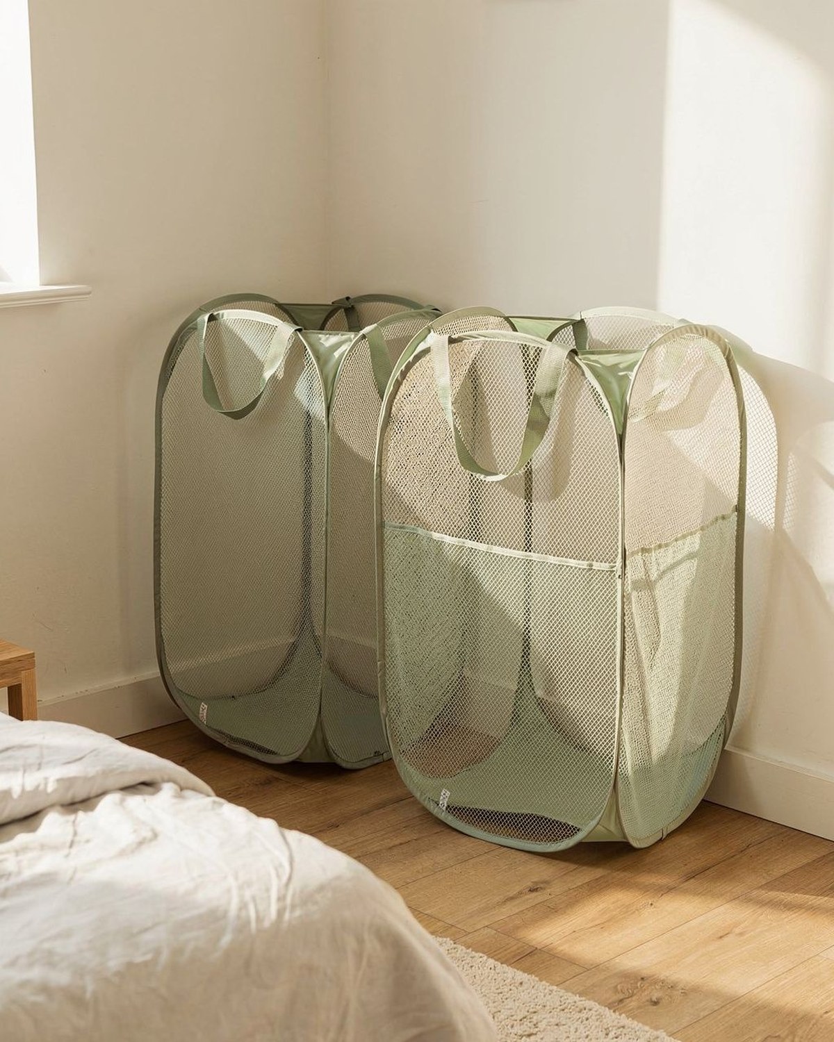 Two tall collapsible mesh pop-up laundry hampers with handles, one navy and one grey, standing open then folded flat.