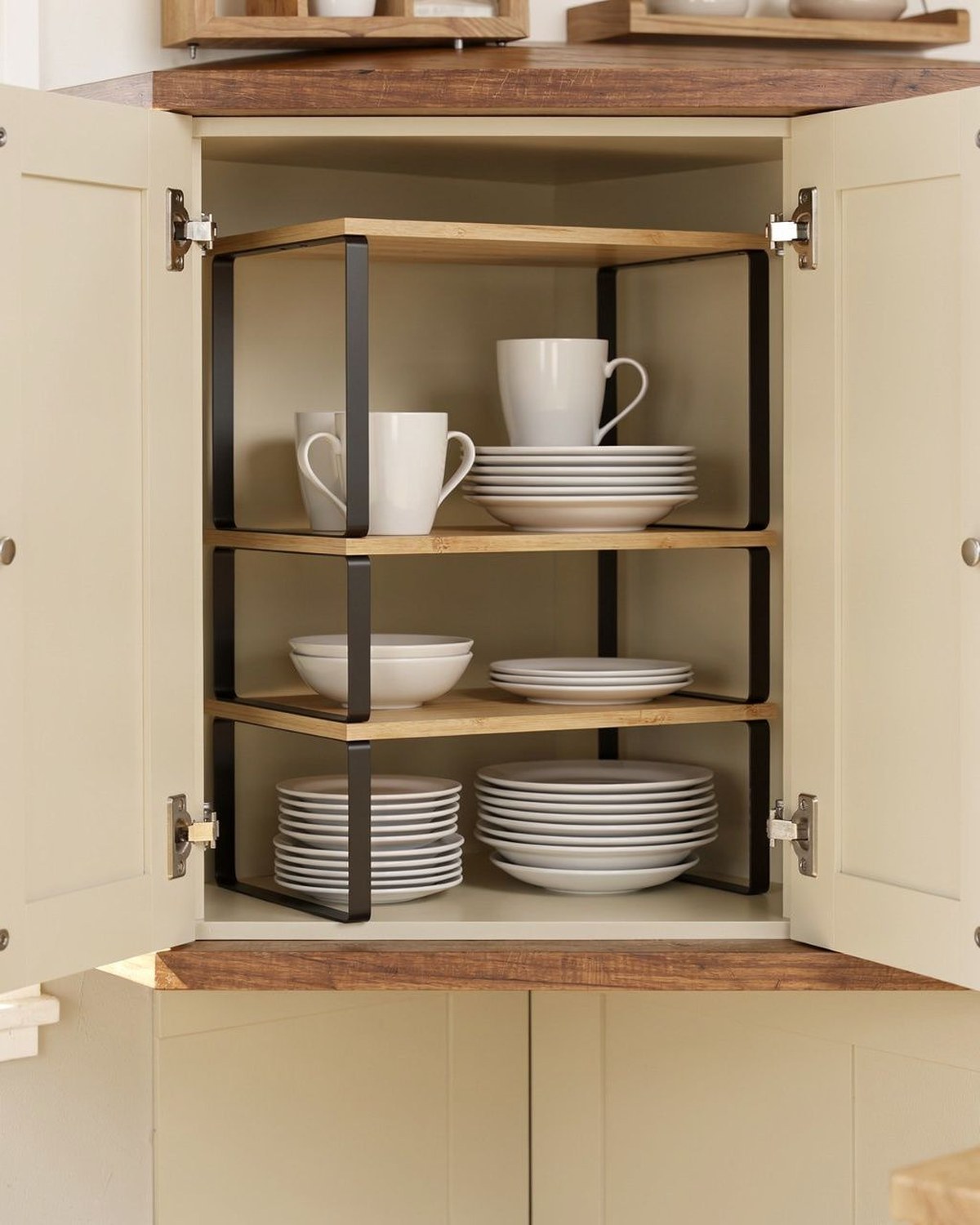 Two stackable metal-and-wood shelf risers in ink-black and natural beige doubling the vertical space inside a cabinet.