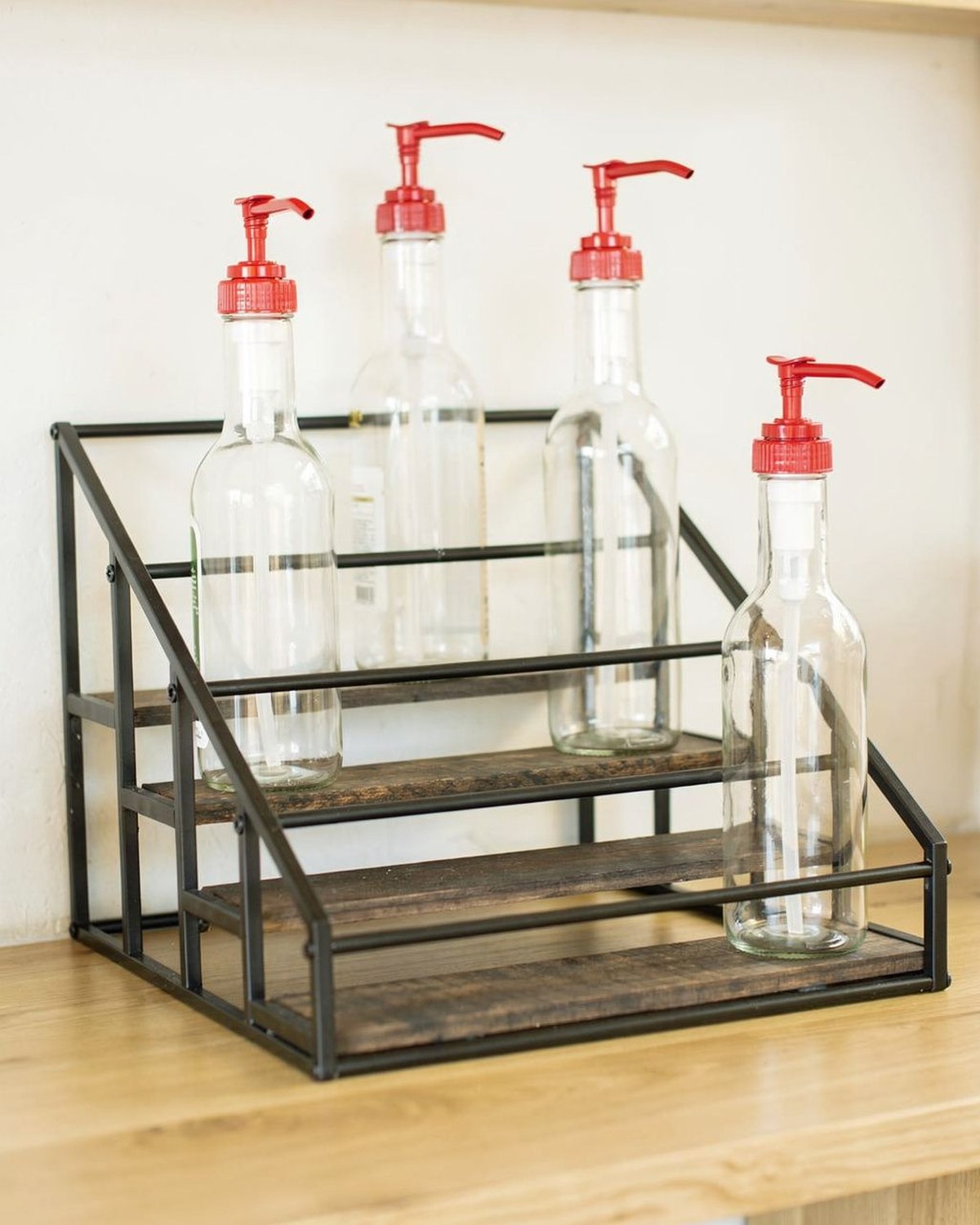 A tiered metal rack lined with pump syrup bottles, displaying flavored-syrup bottles like a cafe back bar.