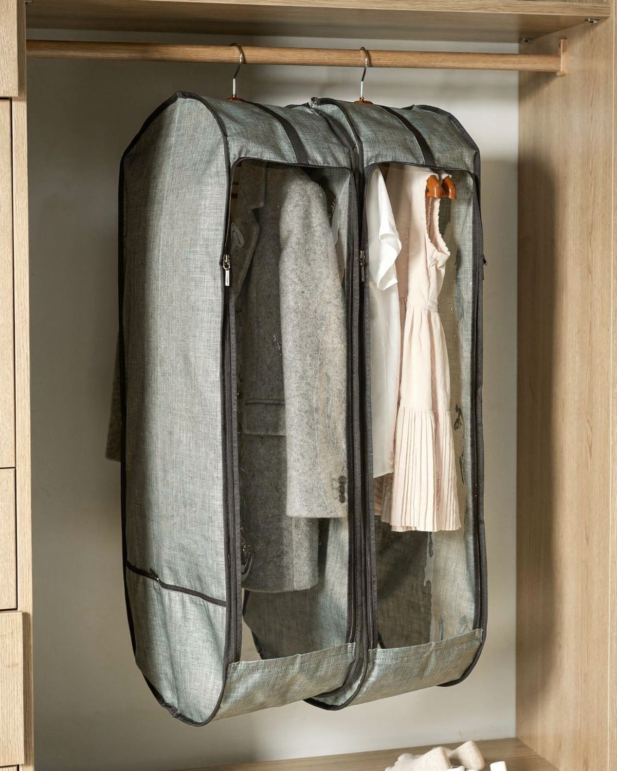 Two long breathable garment bags hanging on a closet rod protecting coats and dresses