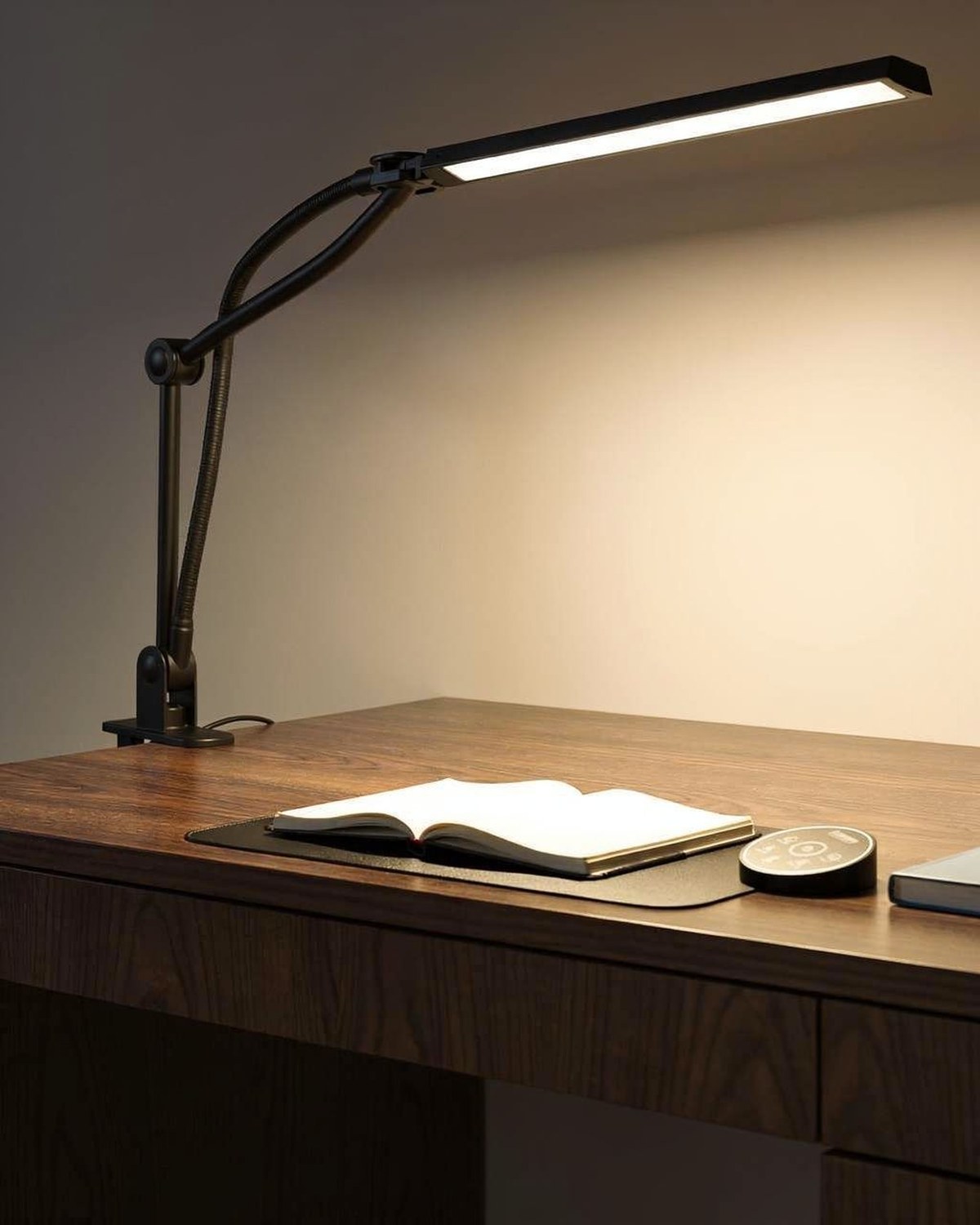 Black swing-arm architect desk lamp clamped to the edge of a work desk