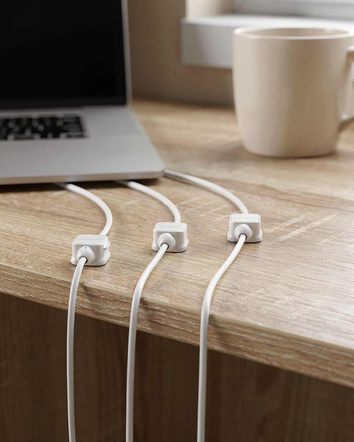 Small magnetic cable clips holding charging cords along the edge of a dorm desk