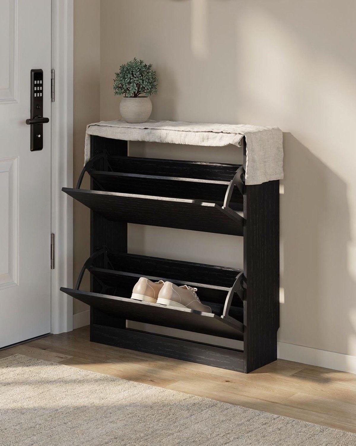 Slim shoe storage cabinet with two flip-down drawers standing against a wall